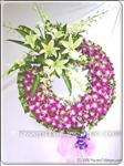 This lovely arrangment of purple orchids is accessed with white lilies and assorted greens. Appropriate for the funeral service. Arrangement is delivered with an easel for display. Approximately 60cm diameter.The delivered stand is 1.5m high
